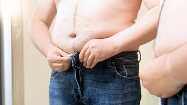 Jovem gordo tentando usar jeans apertados — Fotografia de Stock