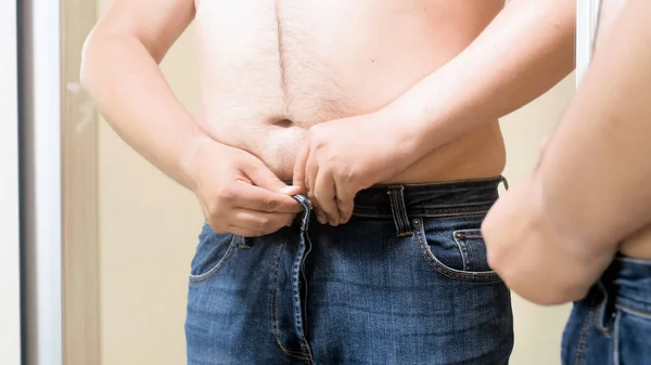 Nahaufnahme Foto von hemdlosen dicken Mann trägt enge Jeans am Spiegel — Stockfoto