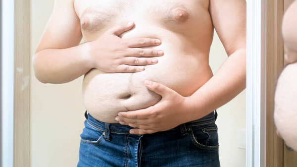 Closeup photo of obese man holding hands on big fat tummy