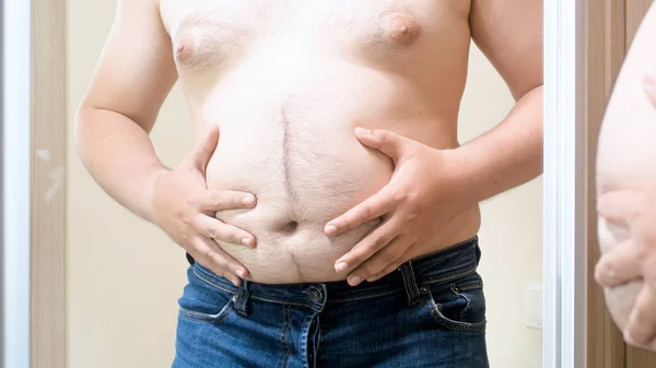 Jovem sem camisa homem com gordura peludo barriga em pé no espelho — Fotografia de Stock