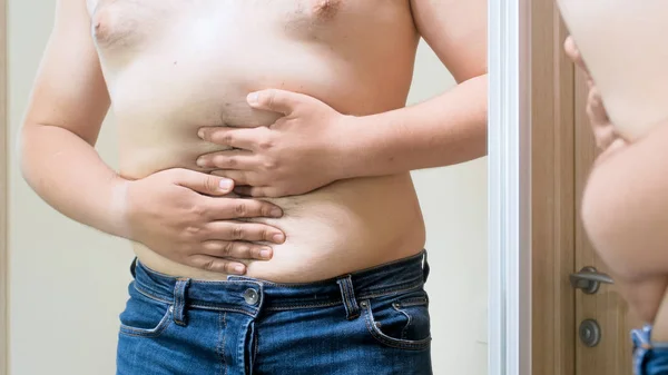 Foto close-up de jovem tentando caber barriga grande em jeans apertados — Fotografia de Stock