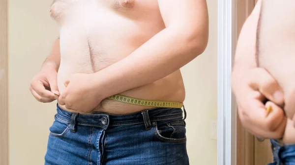 Jovem gordo com barriga de cerveja medindo sua cintura — Fotografia de Stock