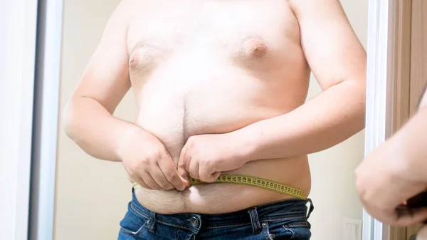 Młody gruby mężczyzna pomiaru jego ogromny brzuch z taśma pomiarowa — Zdjęcie stockowe