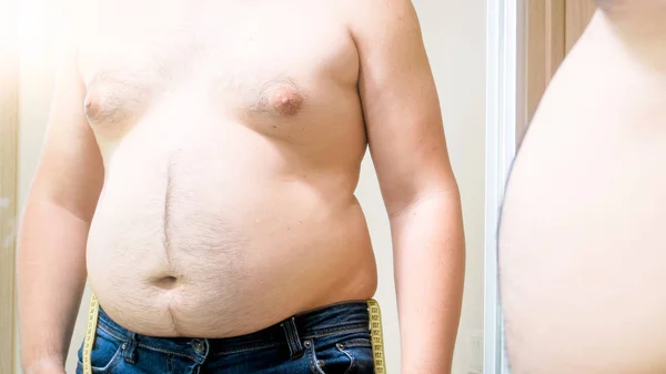 Primo piano foto di uomo grasso con grande pancia e ginecomastia guardando riflesso nello specchio — Foto Stock