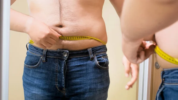 Citra dekat dari anak muda gemuk yang mengukur tubuh di cermin — Stok Foto