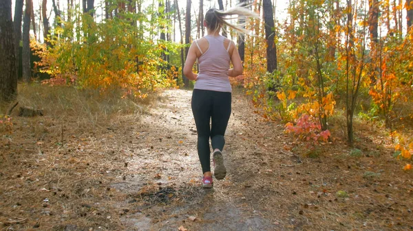 Rear view photo of young woman jogging in autumn forest — Stock Photo, Image