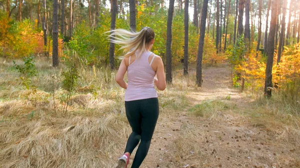 Jovem mulher magra em roupas esportivas correndo na floresta — Fotografia de Stock