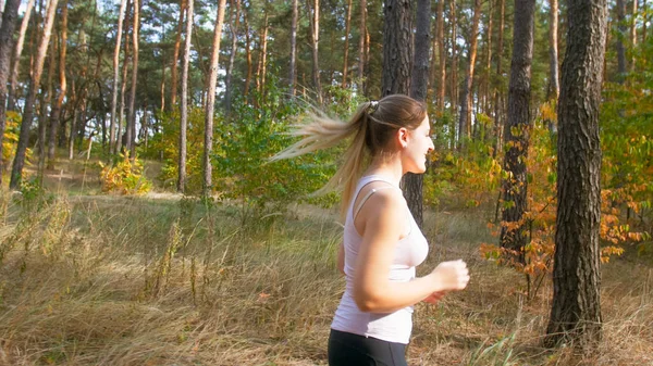 Side view photo of young msiling woman jogging in forest at sunny day — Stock Photo, Image