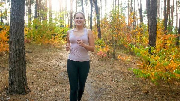 Beautiful young woman in black leggings jogging in forest — Stock Photo, Image