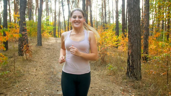 Felice donna sorridente che fa jogging nella foresta nella luminosa giornata di sole — Foto Stock