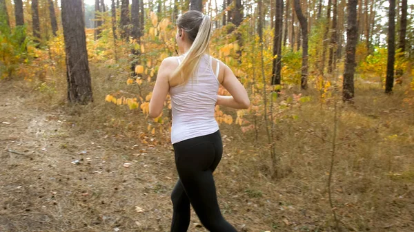 Young blonde woman with ponytail jogging in autumn forest — Stock Photo, Image