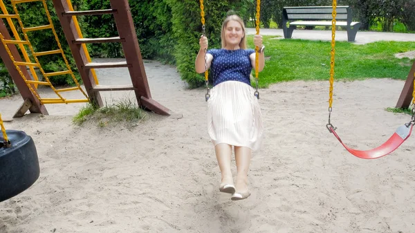 Bella giovane donna che oscilla sul parco giochi per bambini — Foto Stock