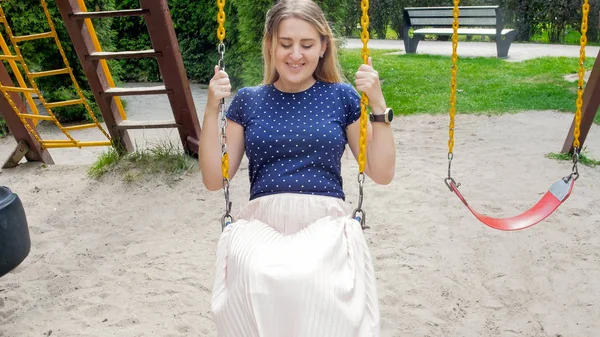 Portret van jonge lachende vrouw op schommel in park — Stockfoto