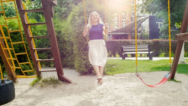 Happy smiling woman swinging in park at sunny day — Stock Photo, Image