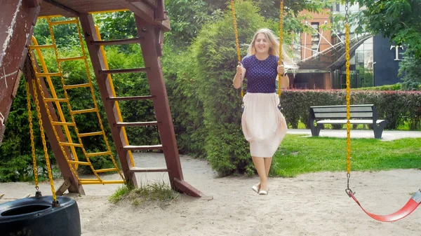 Feliz risita en falda larga divirtiéndose en swing en el parque — Foto de Stock