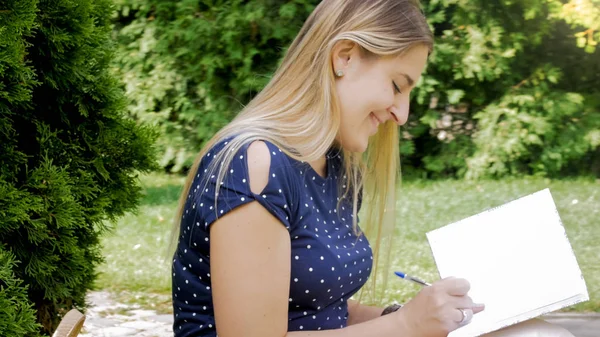 Porträt einer jungen Frau, die im Park Tagebuch schreibt — Stockfoto