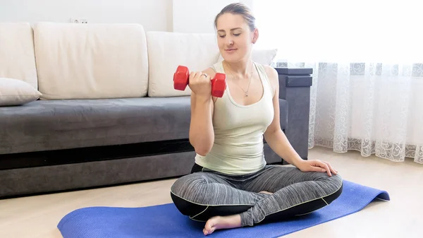 Joven mujer deportiva haciendo ejercicio con pesas en la sala de estar — Foto de Stock