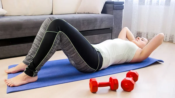 Young woman lying on floor and doing sit-ups — Stock Photo, Image