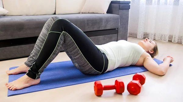 Young tired woman lying on floor after doing sit-ups — Stock Photo, Image