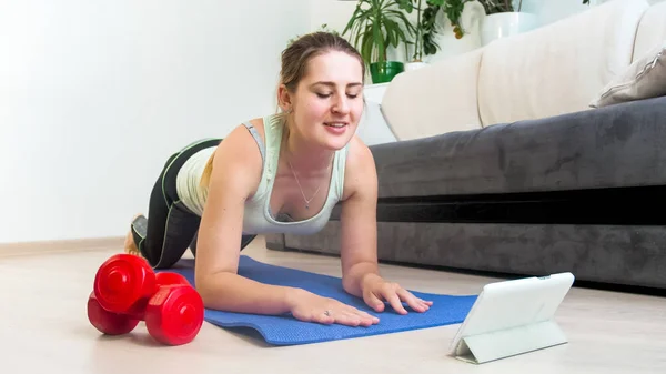 Jeune femme couchée sur tapis de fitness et regardant tablette numérique — Photo