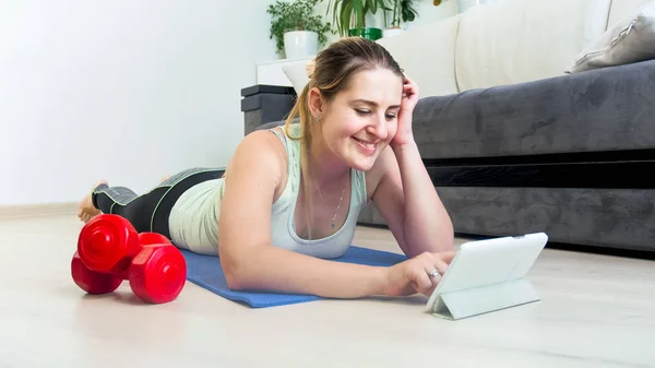 Портрет улыбающейся молодой женщины, болтающей в социальных сетях после тренировки дома — стоковое фото