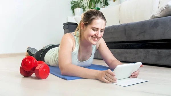 Mooie jonge vrouw met fitness toepassing op digitale tablet — Stockfoto