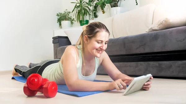 Jonge vrouw trainingsvideo op tablet bekijken voordat u gaat trainen thuis — Stockfoto