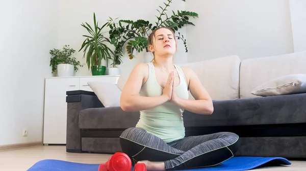 Mujer joven practicando yoga después de hacer ejercicio en la esterilla de fitness — Foto de Stock