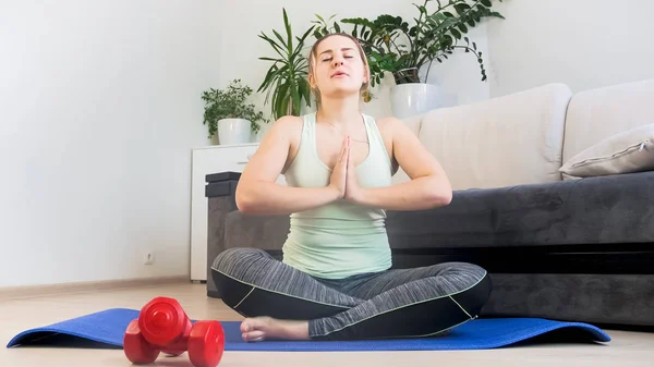 Mujer joven sentada en yoga de loto posando y respirando profundamente — Foto de Stock