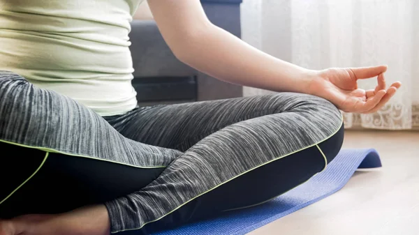 Imagem de close-up da jovem mulher atlética meditando no tapete de fitness — Fotografia de Stock