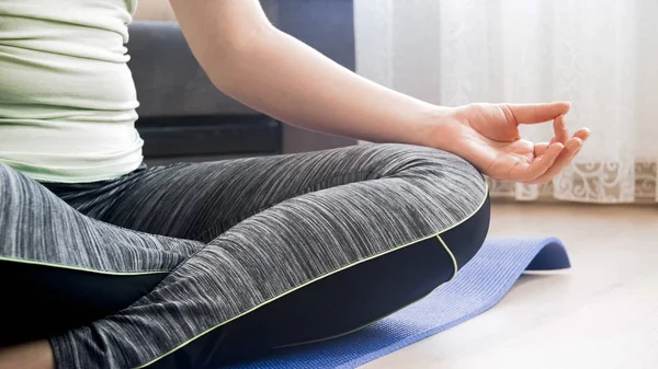 Image rapprochée d'une jeune femme qui médite sur un tapis de fitness à la maison — Photo