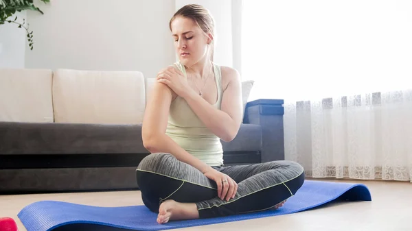 Jeune femme touchant l'épaule douloureuse après l'exercice dans le salon — Photo