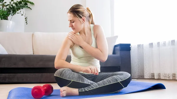 Mujer joven sintiendo dolor en la mano después de hacer ejercicio en casa — Foto de Stock