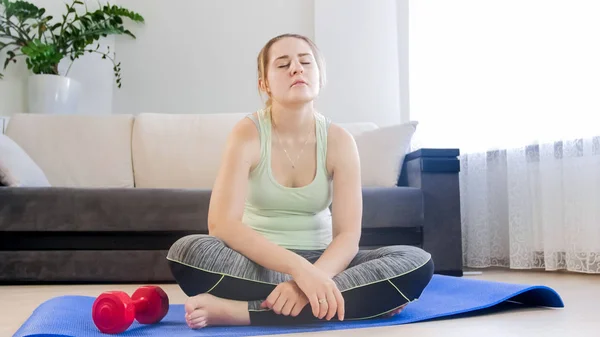 Mujer joven relajándose en la alfombra de fitness después de hacer ejercicio — Foto de Stock