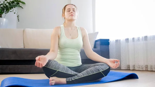 Mulher loira bonita meditando no chão na sala de estar — Fotografia de Stock