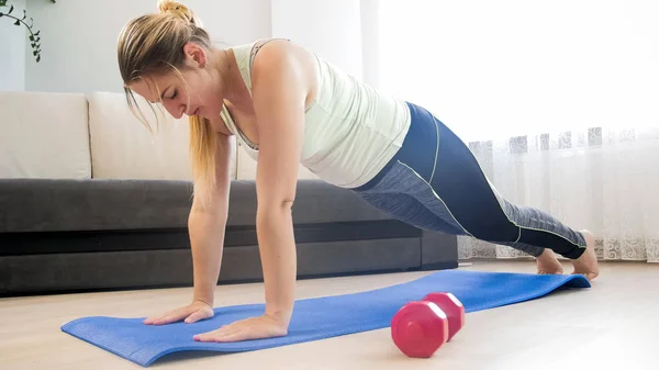 Jonge blonde vrouw doen push-ups op fitness mat thuis — Stockfoto