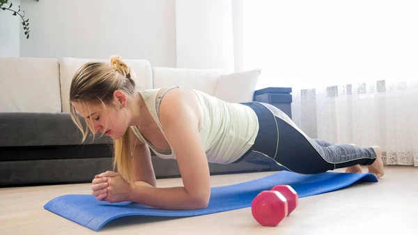 Jovem cansada fazendo exercício de prancha no tapete de fitness em casa — Fotografia de Stock