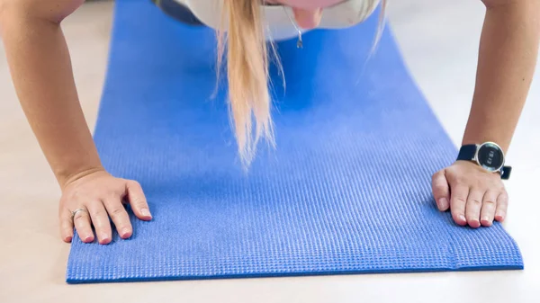 Foto de primer plano de una mujer joven haciendo flexiones en la alfombra de fitness en casa — Foto de Stock