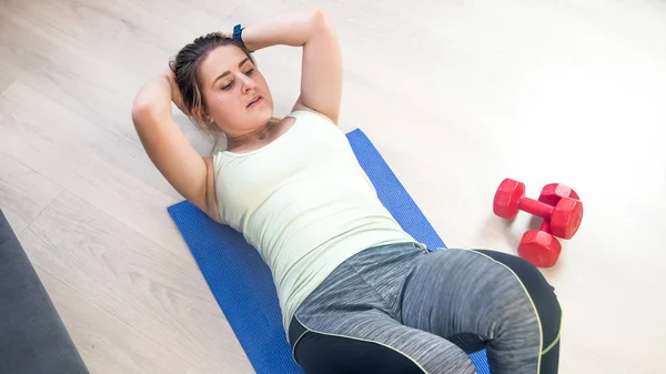 Mujer atlética joven haciendo abdominales en el suelo de madera — Foto de Stock