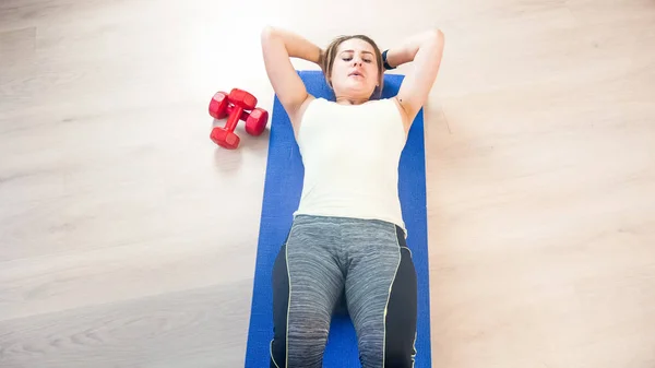 Mooie jonge vrouw liggend op fitness mat en abs-sit-ups doen — Stockfoto