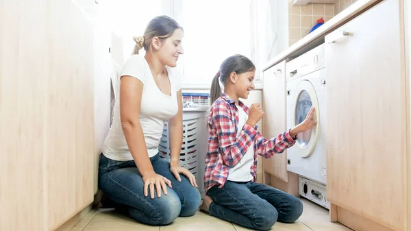 Щаслива усміхнена дівчина-підліток допомагає матері в пральні — стокове фото