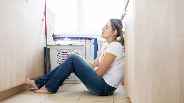 Verärgerte Hausfrau lehnt an Waschmaschine in Waschküche — Stockfoto