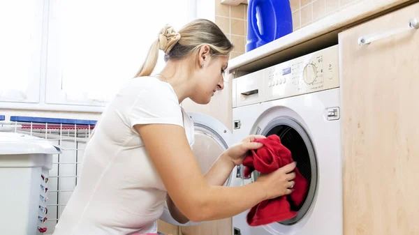 Portrait de jeune femme au foyer prend serviette rouge de la machine à laver — Photo