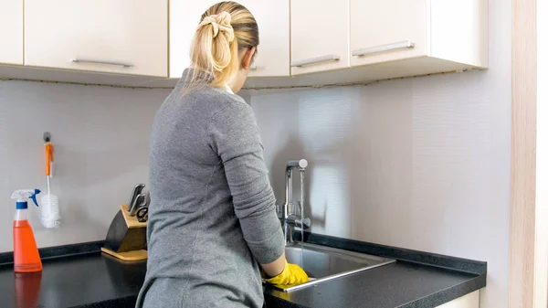 Vista trasera foto de la joven ama de casa de pie en el fregadero de la cocina —  Fotos de Stock