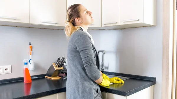 Уставшая женщина, стоящая на кухне после мытья посуды — стоковое фото