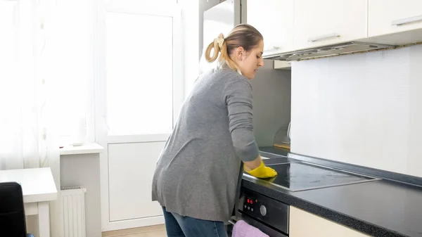 Ibu rumah tangga pirang muda membersihkan dan mencuci meja dapur — Stok Foto