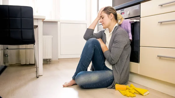 Exhausted young housewife sitting on floor and crying — Stock Photo, Image
