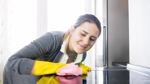 Vackra leende hemmafru rengöring målat glas ytan av elektrisk kokplatta — Stockfoto
