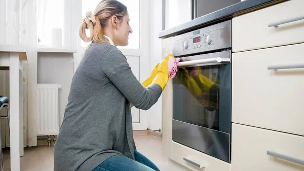 Portret van de jonge blonde huisvrouw wassen en schoonmaken van de keuken met doek — Stockfoto