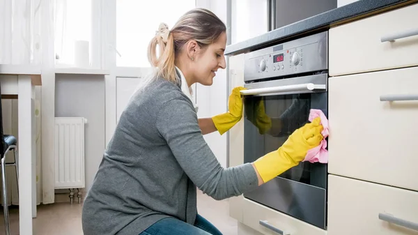 Mulher sorridente bonita doung tarefas domésticas e cozinha de limpeza — Fotografia de Stock